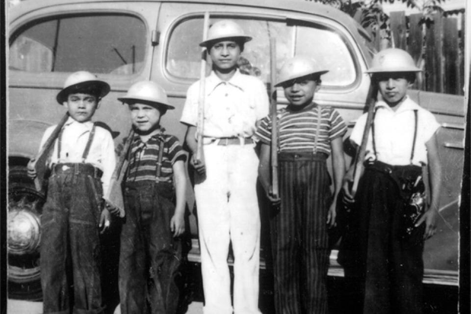 young boys play soldier holding wooden rifles and wearing helmets